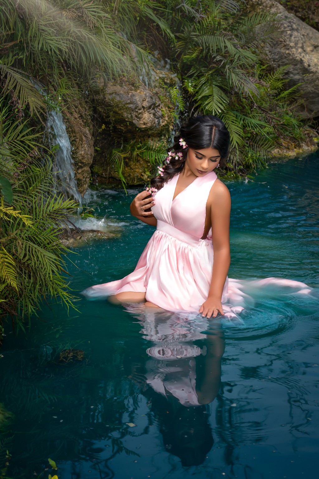 Ilyana standing in the water wearing a soft pink quinceañera gown